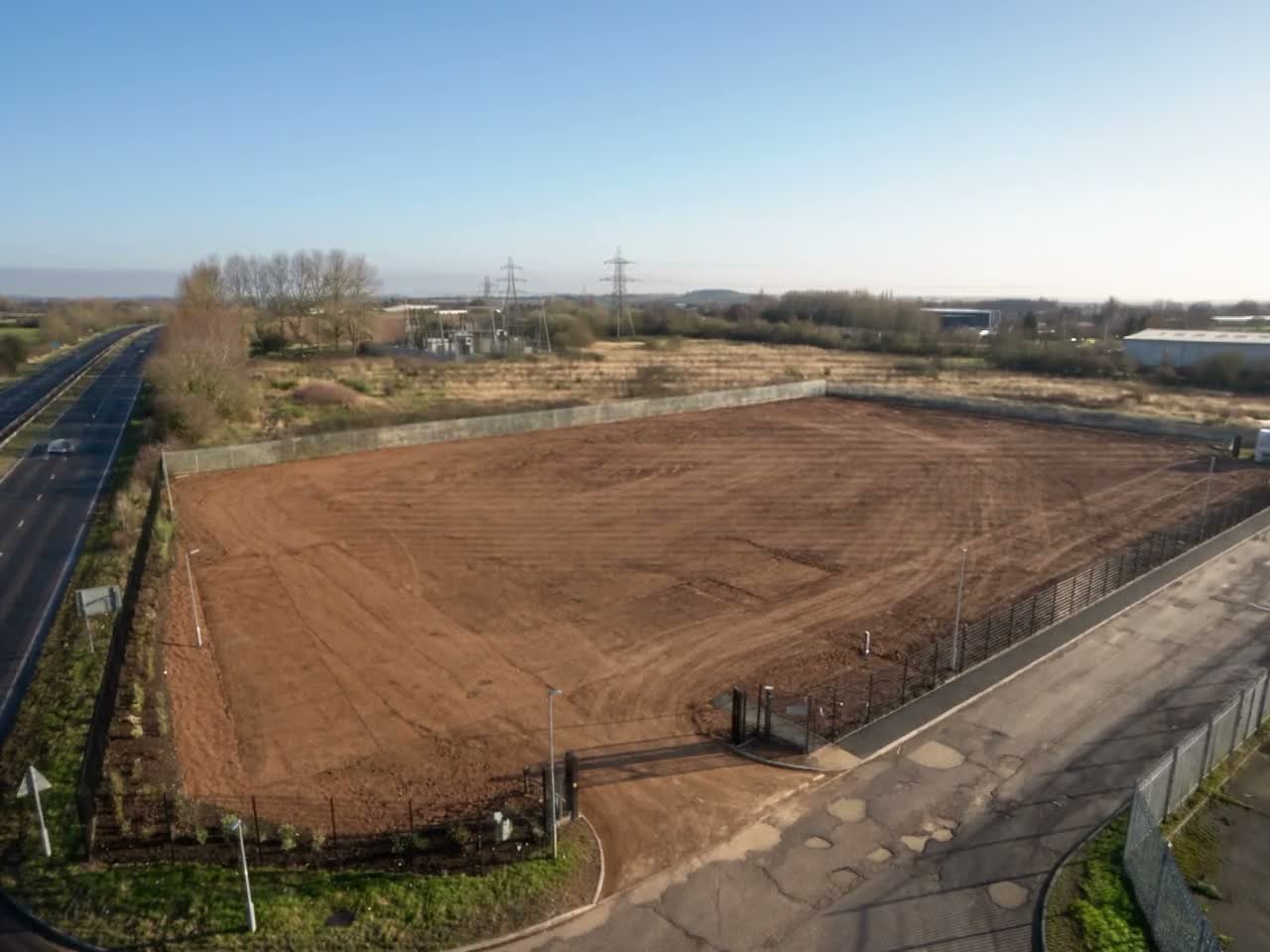 Still frame: cleared industrial plot aerial view before the plot-to-operational planning CGI process film plays