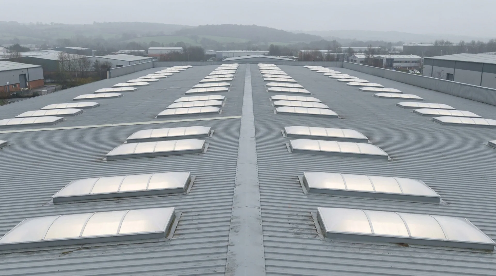 Warehouse roof skylight rhythm CGI showing polycarbonate dome rooflights at consistent grid spacing with daylight hitting the polished interior floor at UK latitude angle